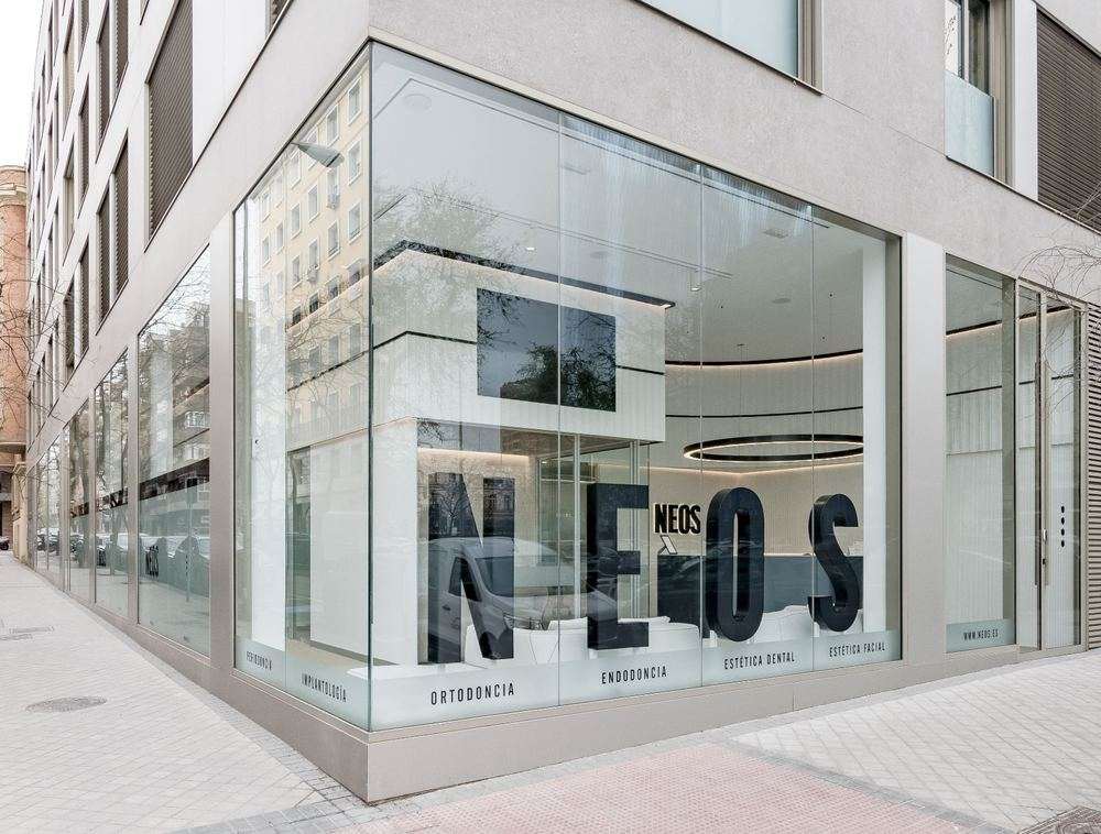Fachada acristalada de la clínica dental NEOS con rótulo corporativo